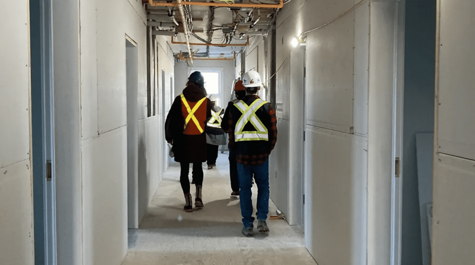 Two people with hard hats walking through construction.