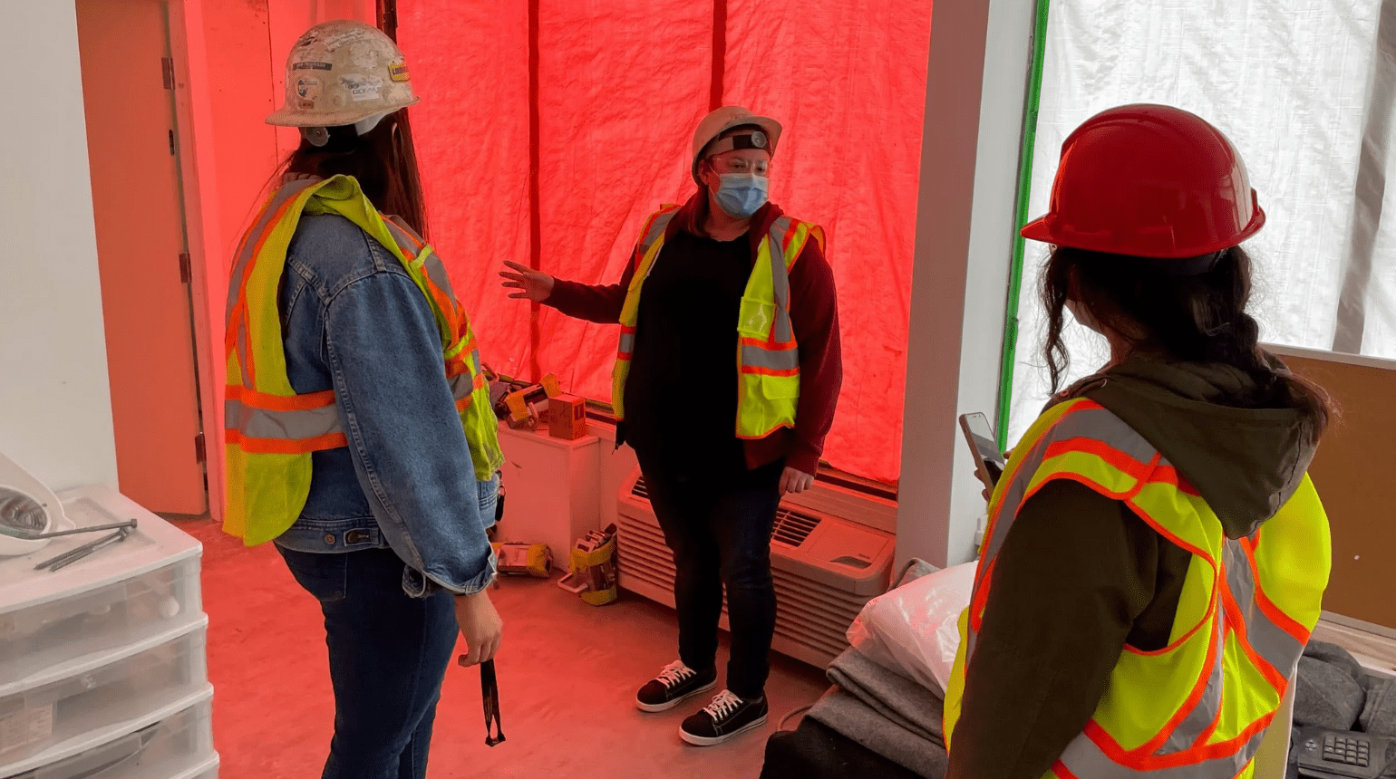 Three people wearing hard hats touring the Kingsway Supportive Housing construction site.