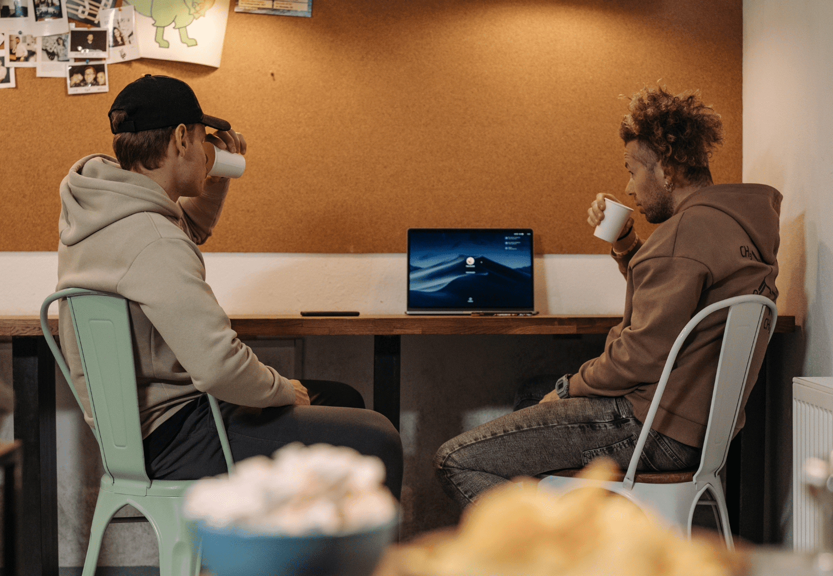 Two men at a cafe looking at a laptop and drinking coffee