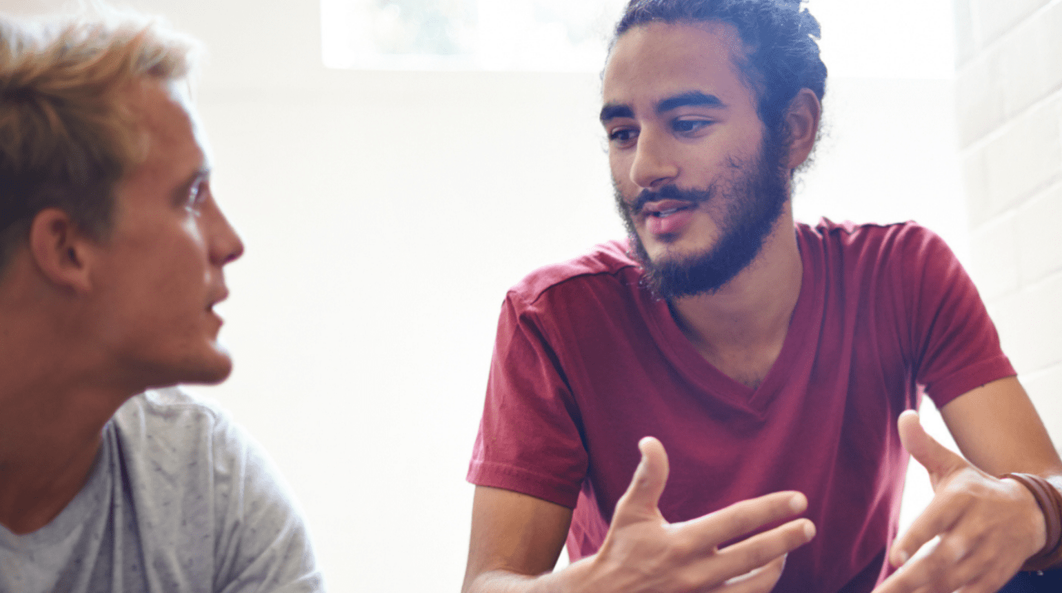 Two men sitting; one is talking to the other.