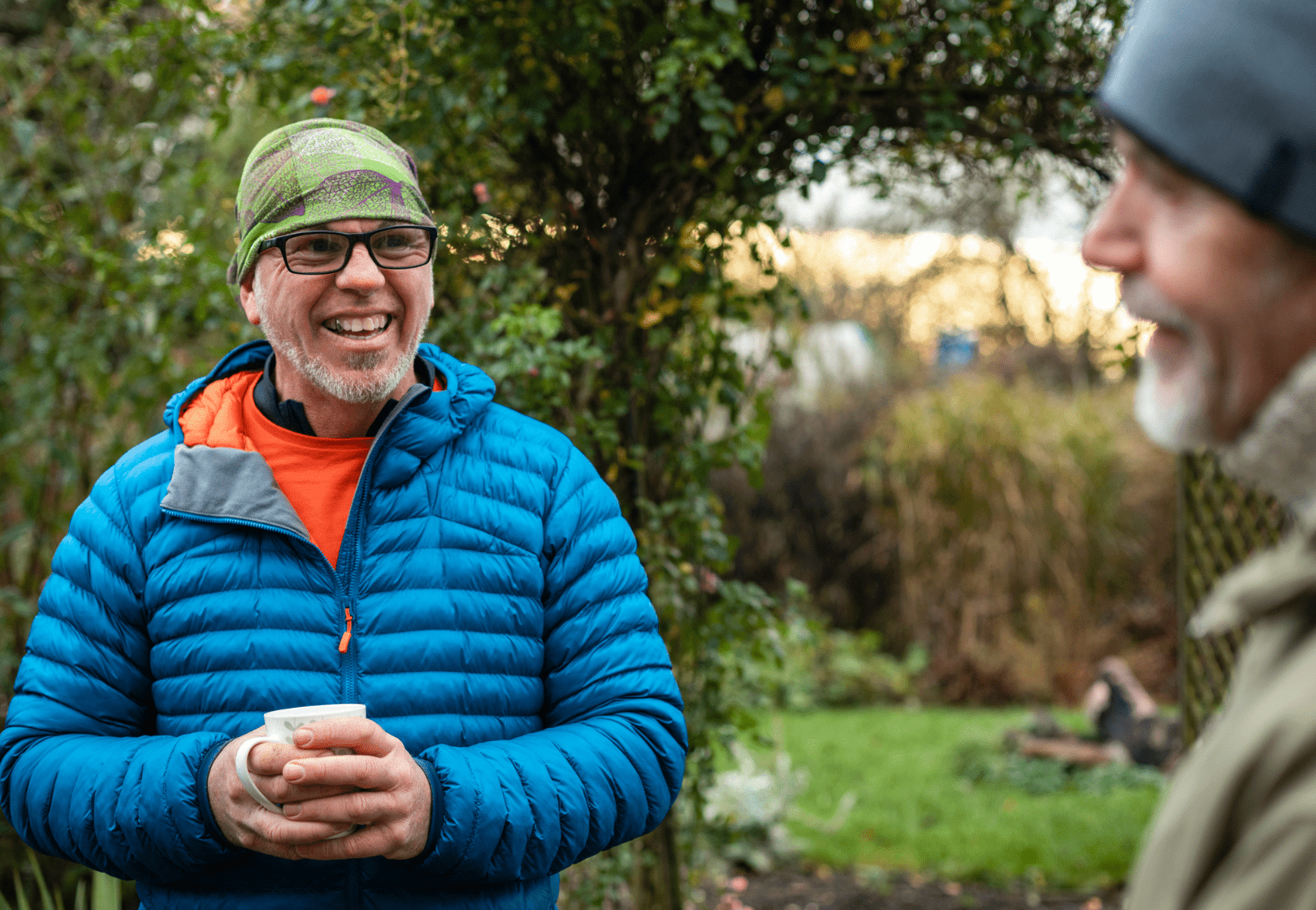 Two men outside talking over coffee