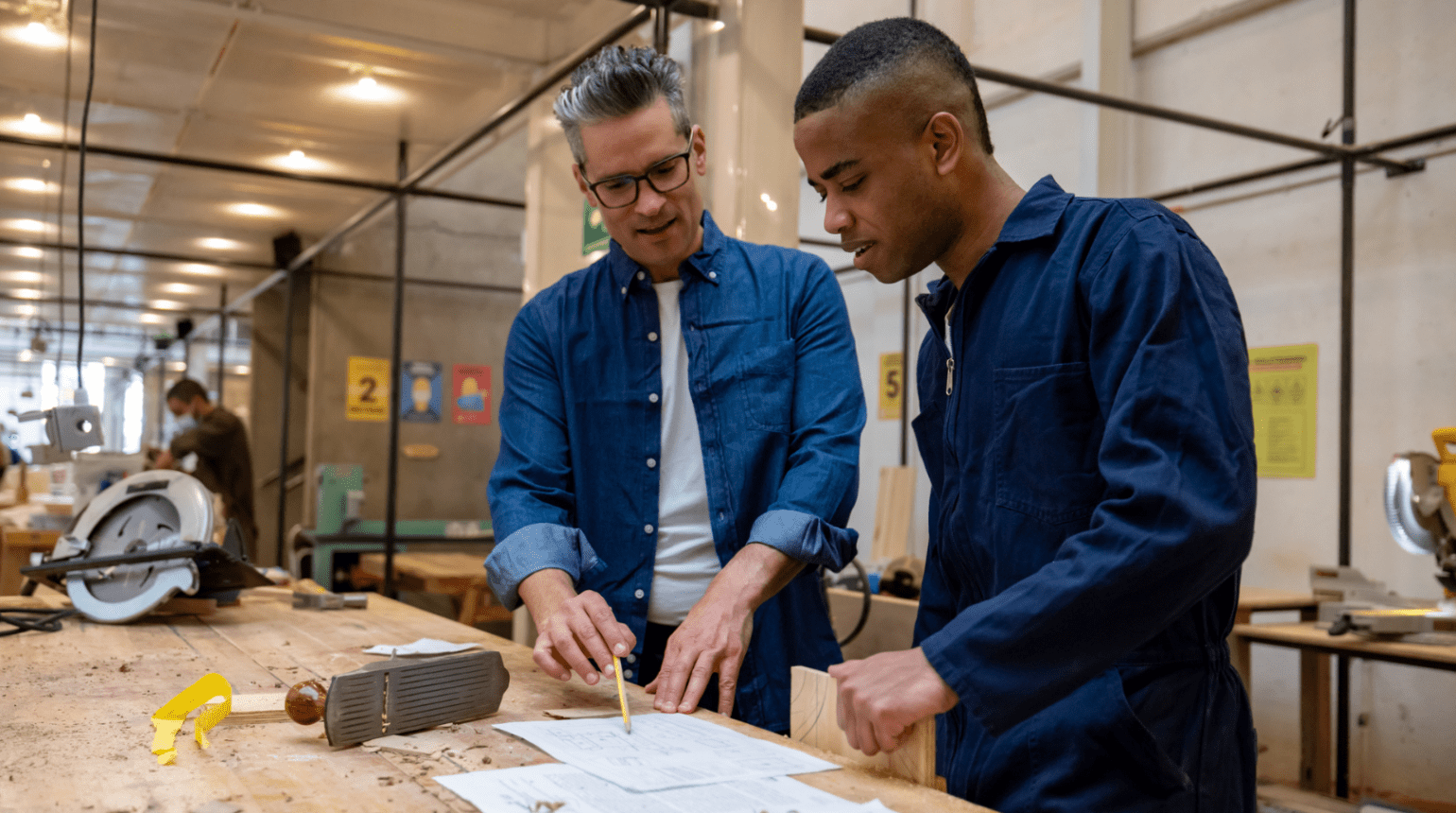 Carpenters looking at sketches in workshop