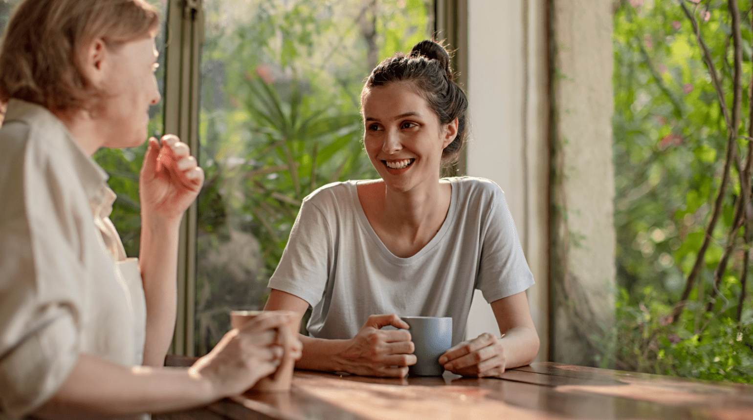 Two women sitting a table with mugs