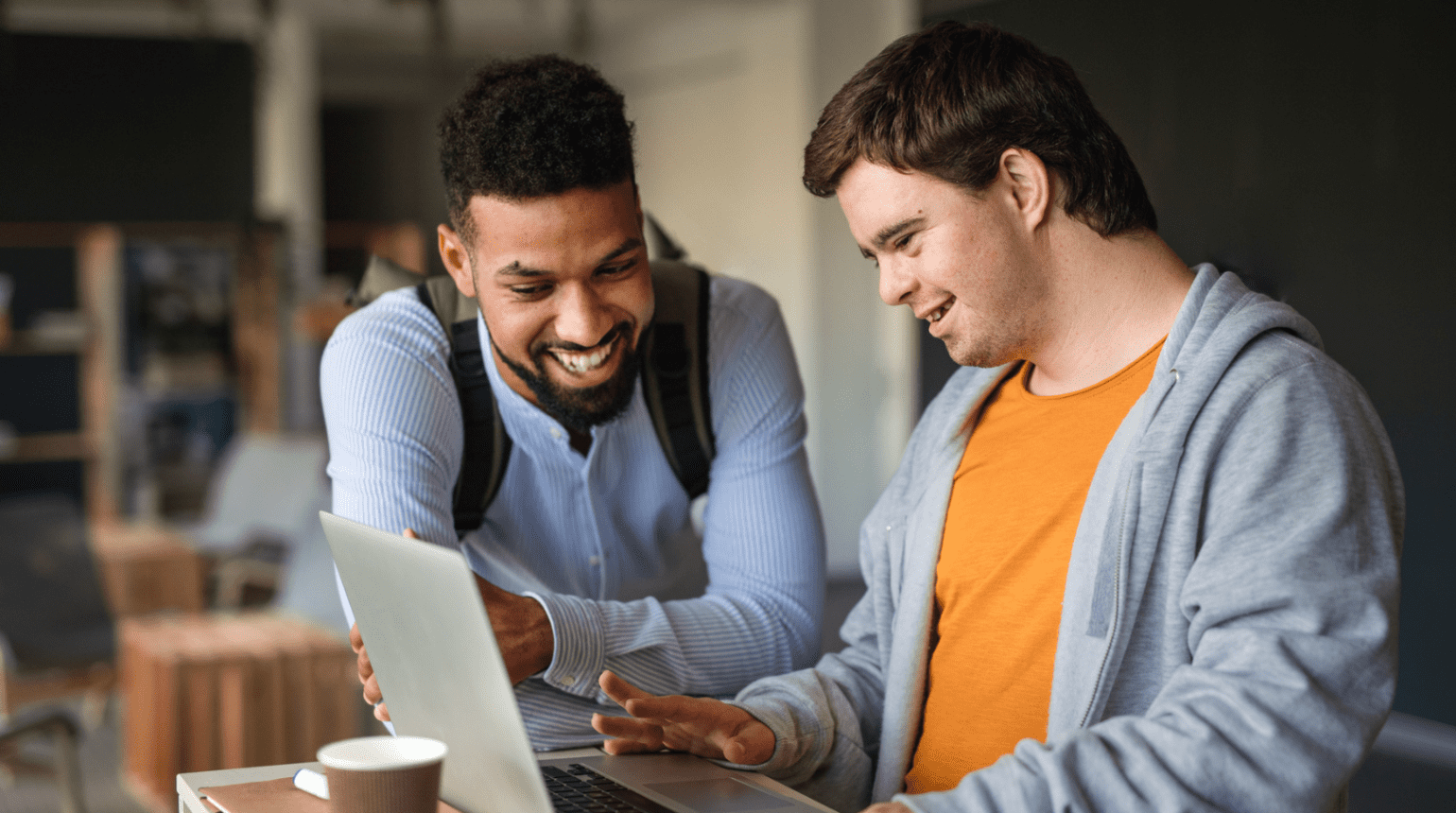 Two men at a laptop in a coffee shop