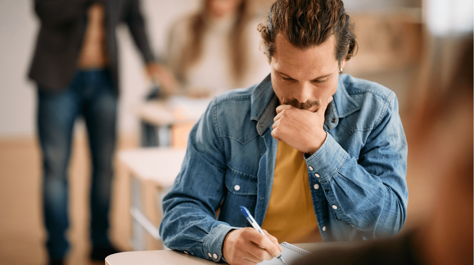 Man sitting in a classroom writing on paper