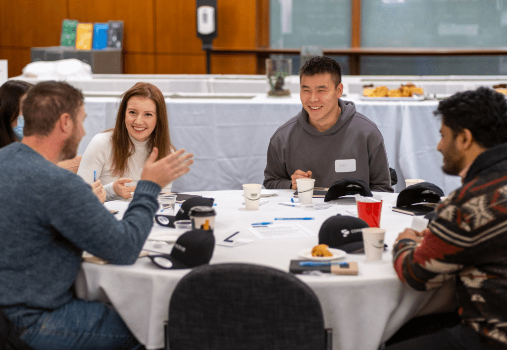 Five Connective staff sit at a circular event table, engaged in animated conversation.