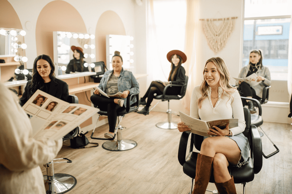 5 women sitting in a hair salon with manuals. 