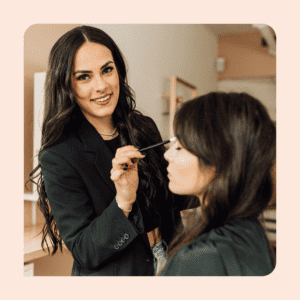 one woman putting eye shadow on another woman. 