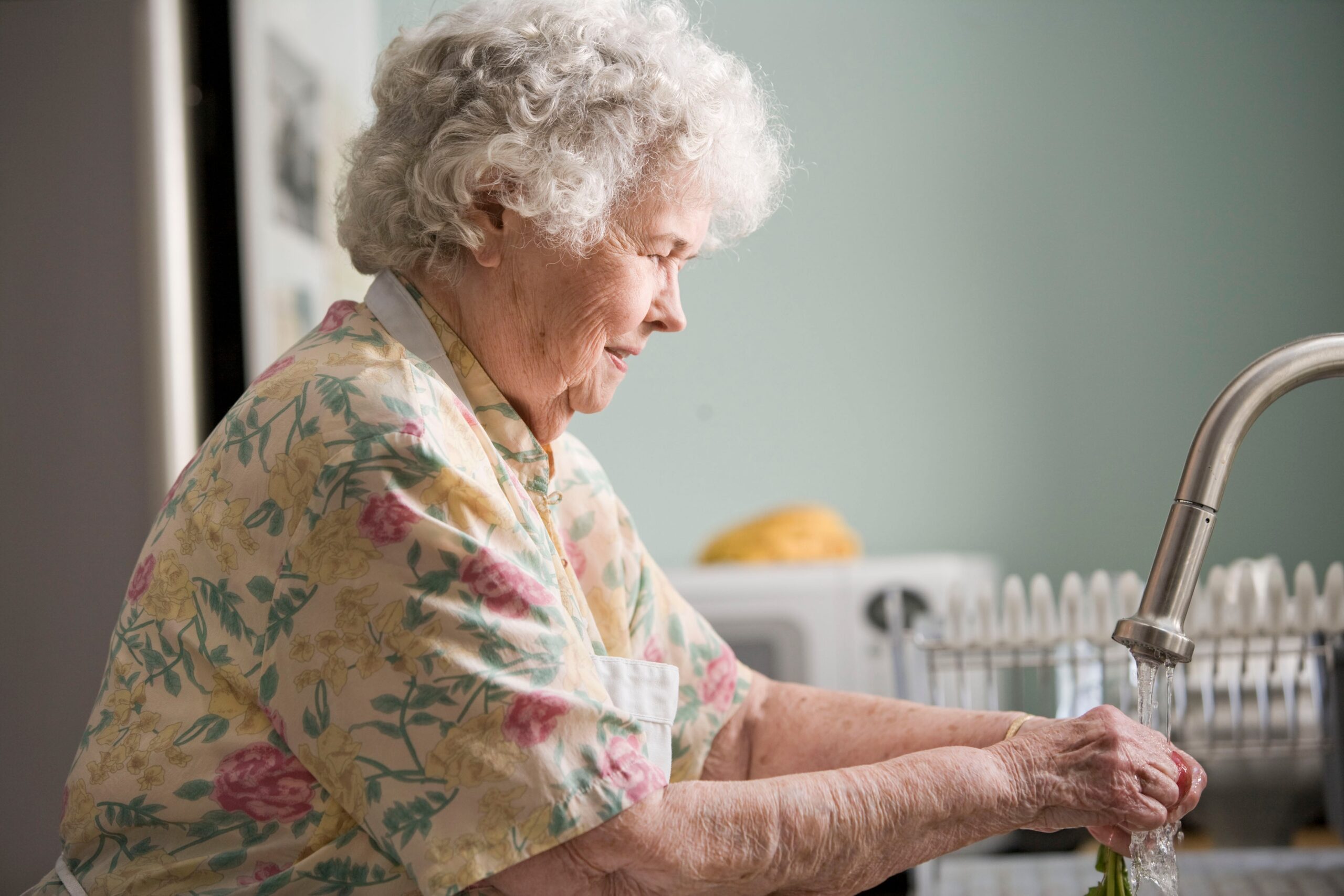Older woman washing dishes.
