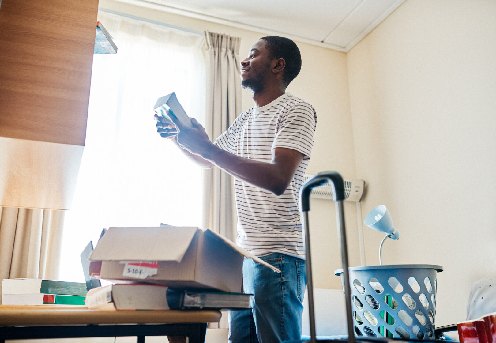 Cropped shot of a cheerful young man unpacking his stuff after arriving at his new home inside during the day