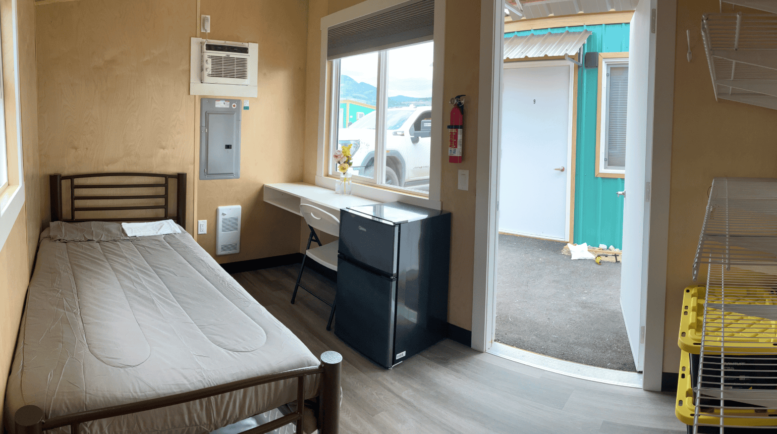 inside modular unit, showing bed, desk and fridge
