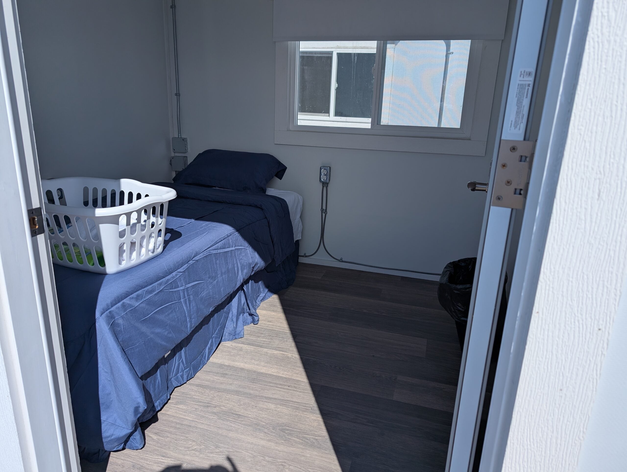 Single room with a single bed and laundry basket