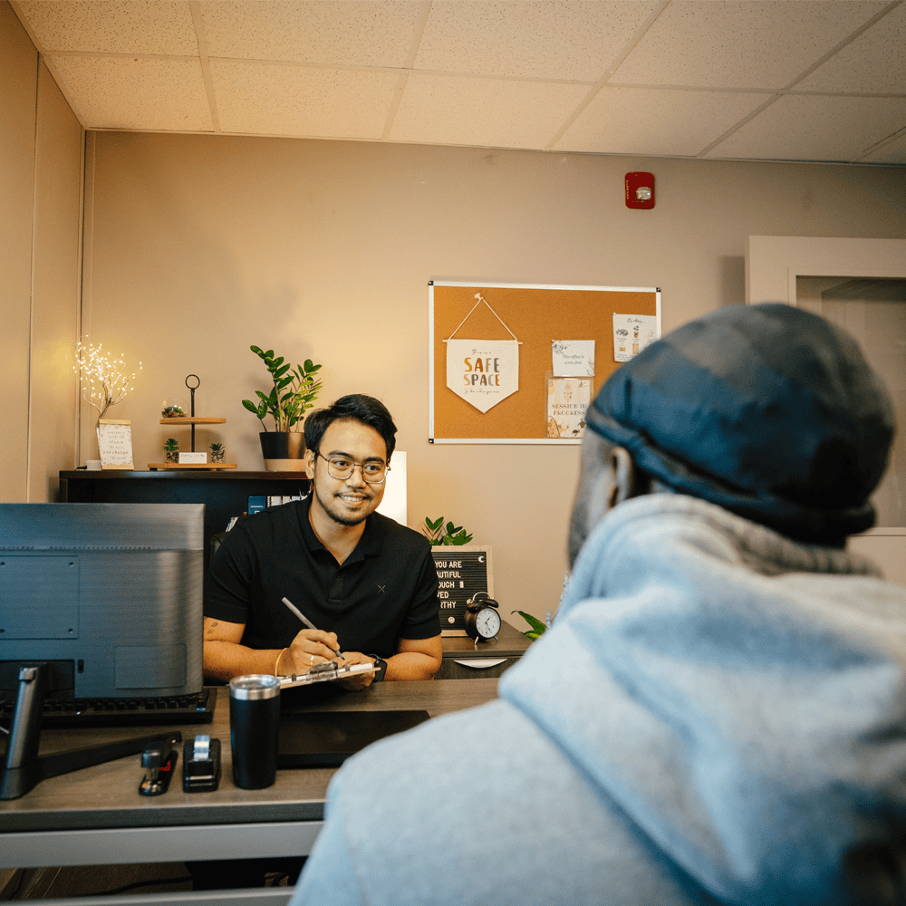 A tenant support worker takes notes during a meeting with a program resident. 