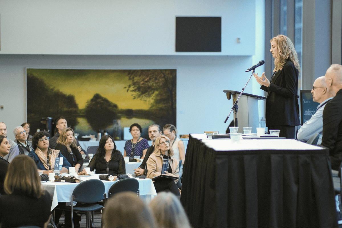 woman speaking to room of professionals